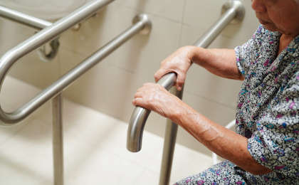 Senior woman uses support rails installed in the bathroom.