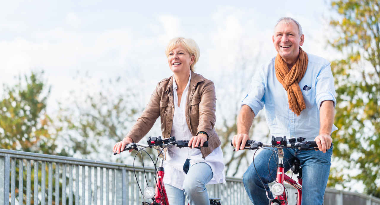 Senior couple on bicycles exercising to prevent stroke