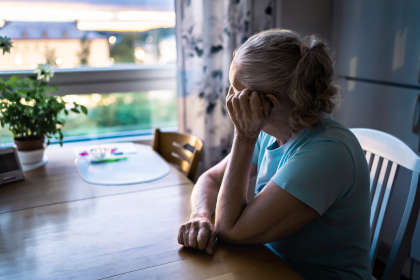 Sad old woman. Depressed lonely senior lady with alzheimer, dementia, memory loss or loneliness. Elder person looking out the home window. Sick patient with disorder. Pensive grandma.