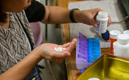 Woman sorting pills into medical pill boxes.