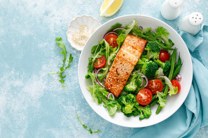 Grilled salmon fish fillet and fresh tomato vegetable salad with lettuce, arugula, broccoli and green beans. Healthy food, mediterranean diet