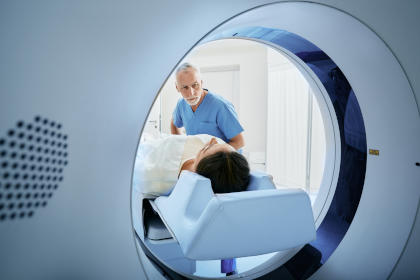 CT scan technologist overlooking patient in Computed Tomography scanner during preparation for procedure. Woman patient going into CT scanner