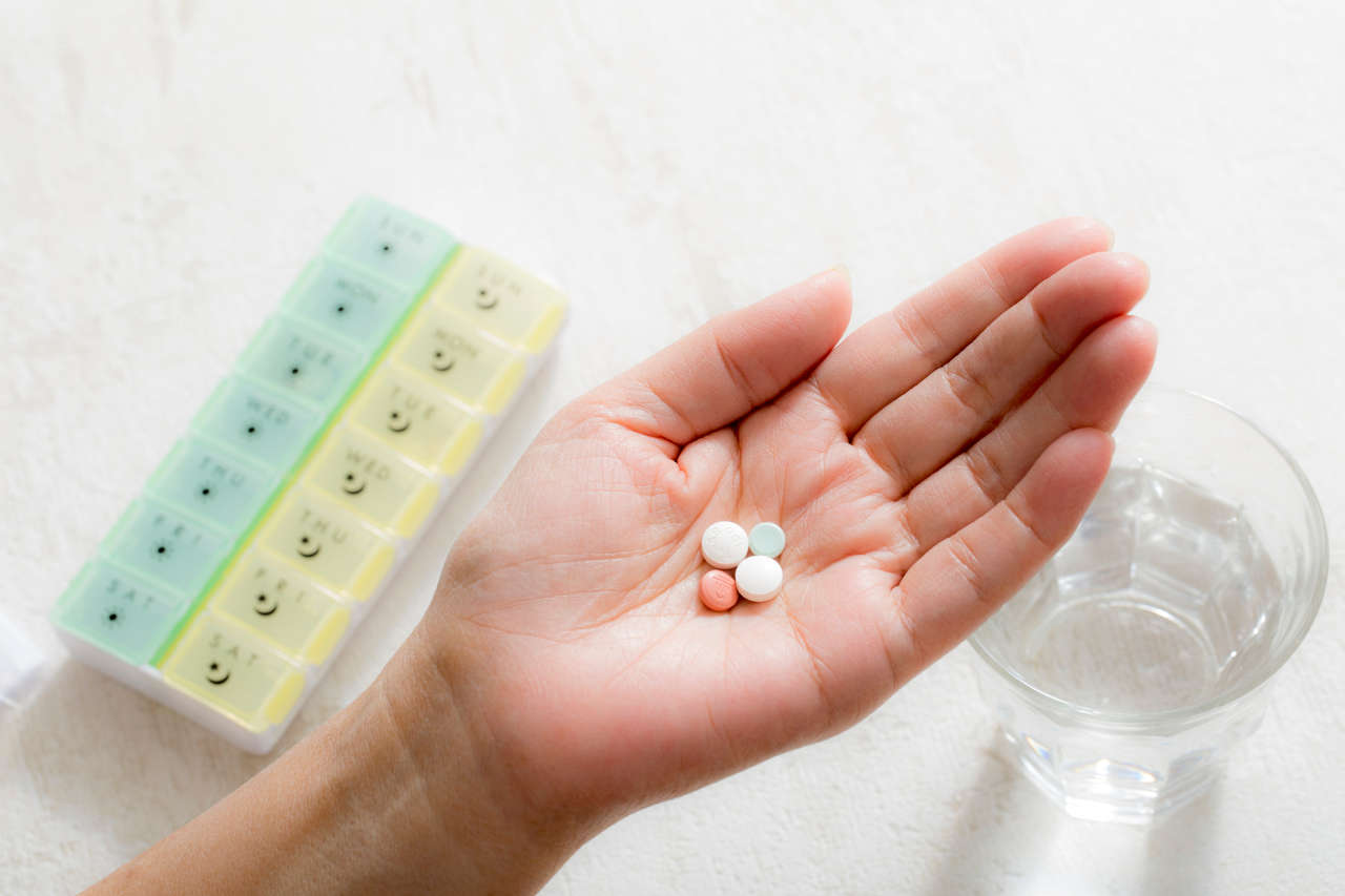 Woman taking meds from a pill dispenser