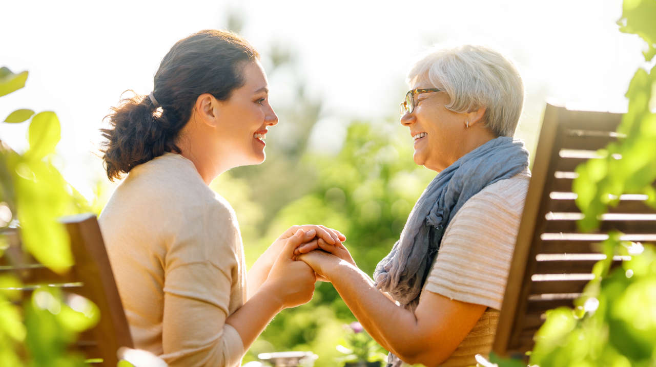 Family caregiver sitting and holding hands with care recipient