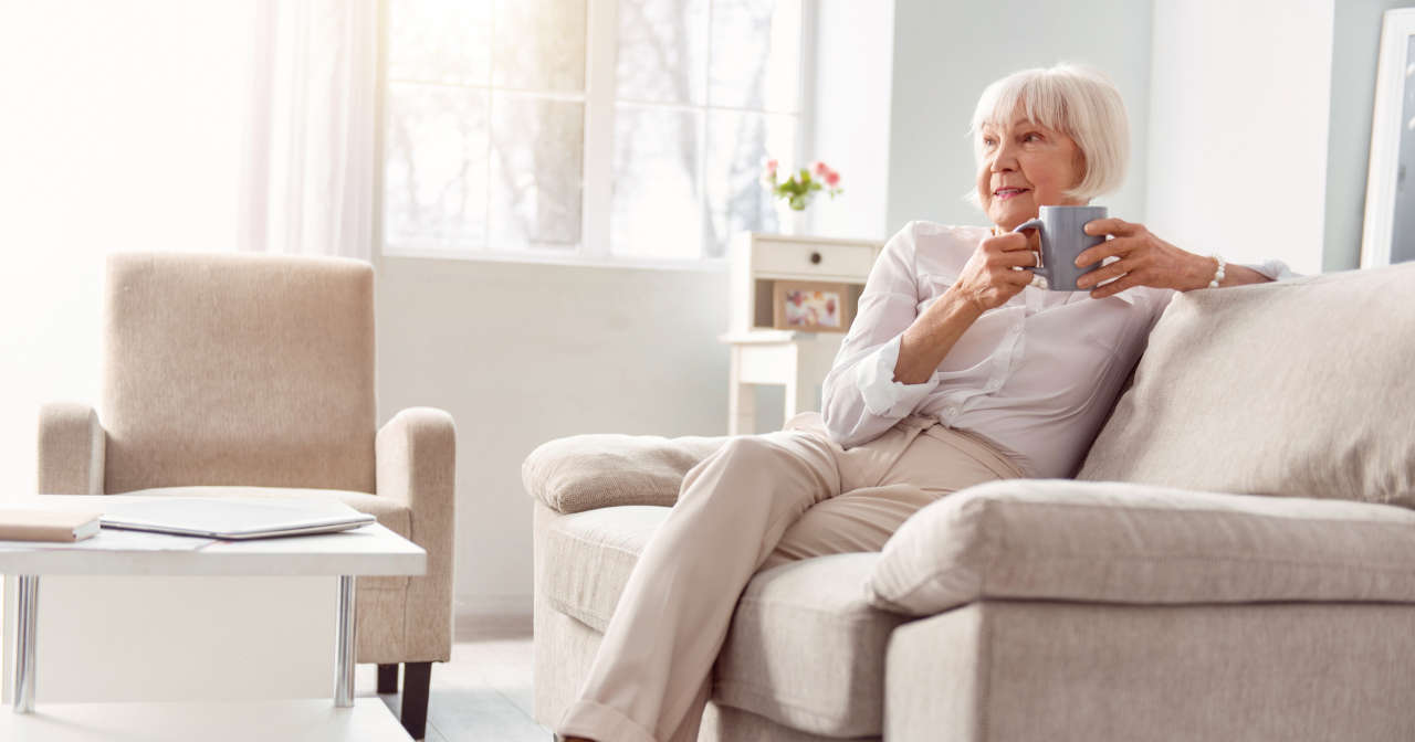 Petite elderly woman drinking coffee in her living room