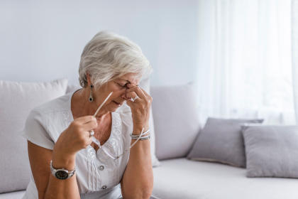 Elderly woman suffering from migraine headache at home